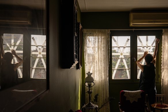 Seorang penduduk menutupi jendela untuk mencegahnya pecah di tengah serangan AS-Israel yang sedang berlangsung di Tehran, Iran.