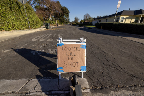 A sign reading ‘looters will be shot’ stands in a mandatory evacuation zone at the Eaton Fire.