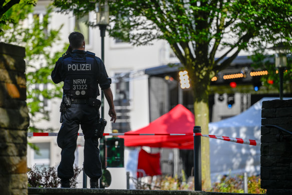 Police investigators stand at the site of the deadly stabbings that left three dead and eight injured.