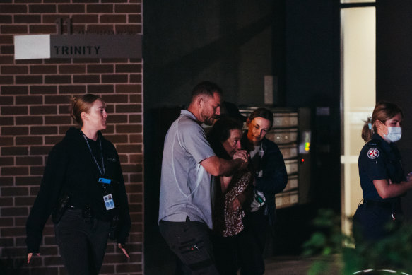 A distressed woman is escorted to an ambulance at the scene.