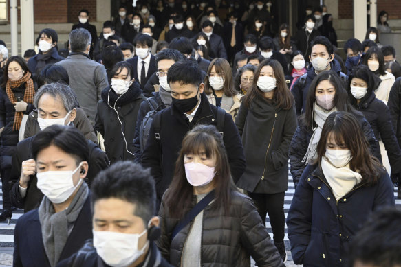 Taşıtlar, Ocak ayında COVID kuralları düşürülmeden önce Tokyo İstasyonu dışında maske takıyor.