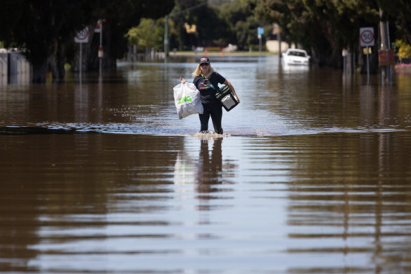 A woman carries her belongings through the floodwater in South Shepparton on Monday.