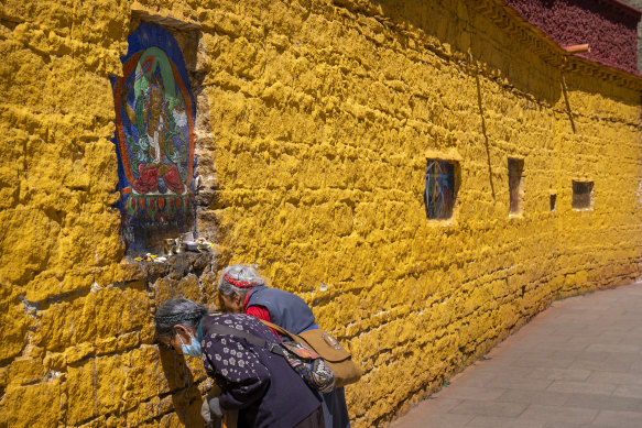 Members of the Tibetan Buddhist faithful pay their respects at a holy site at the base of the Potala Palace in Lhasa, Tibet. The Palace is closed due to the first cases of COVID in the region since the start of the pandemic.