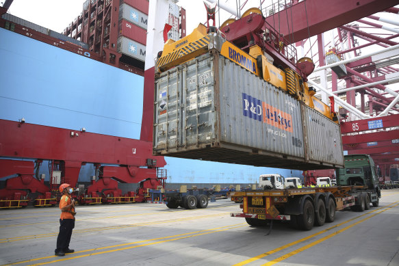 A worker wearing a face mask to protect against the coronavirus guides the loading of a shipping container in China's Shandong Province. 