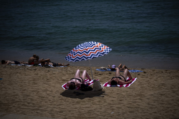 İnsanlar Barselona, ​​İspanya'da bir plajda güneşleniyor.