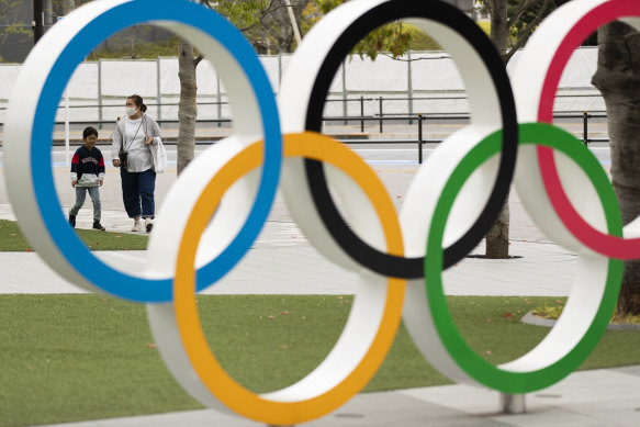 A mother and a boy walk by a display of the Olympic rings at the Japan Olympic Museum in Tokyo.