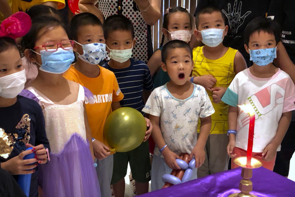Children wearing face masks to protect against the coronavirus watch a performance at a shopping mall in Beijing.