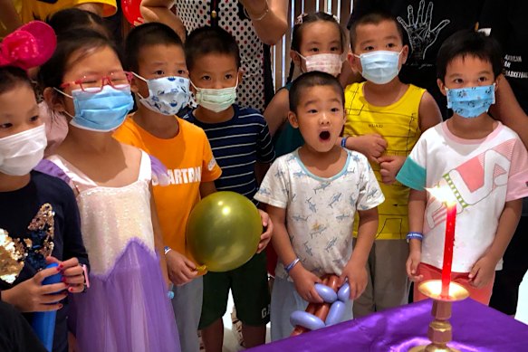 Children wearing face masks to protect against the coronavirus watch a performance at a shopping mall in Beijing.