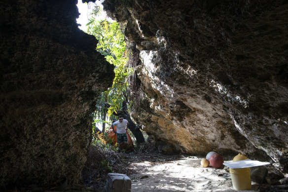 Conservationist Brett Howell drags a sackful of plastic into one the island’s limestone caves.
