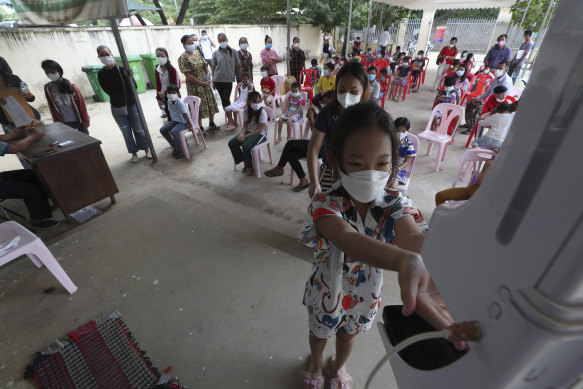 A young girl disinfects her hands before receiving a shot of the Sinovac vaccine at a health centre outside Phnom Penh.