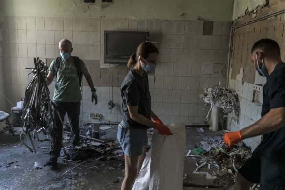 Volunteers clean debris from a building after the strike on Okhmadyt children’s hospital.