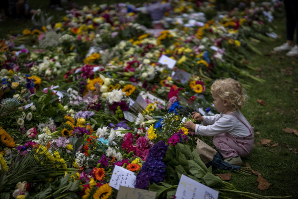 A child touches tributes left for Queen Elizabeth II at the Green Park memorial, where tens of thousands of flowers lay.