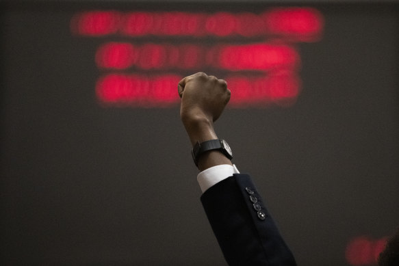 Representative Justin Pearson raises his fist on the floor of the House chamber in Nashville.