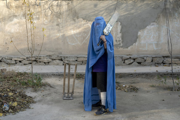 An Afghan woman poses for a photo with her cricket bat in Kabul in 2022.