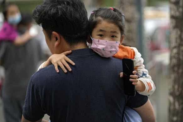 A man carries a child kindergarten in Beijing this week.