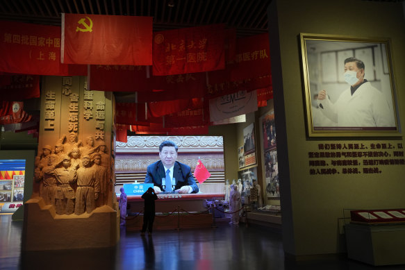 Il presidente cinese Xi Jinping appare sullo schermo vicino a una fotografia che lo ritrae con una maschera che evidenzia la lotta della Cina contro il coronavirus al Chinese Community Party Museum di Pechino.