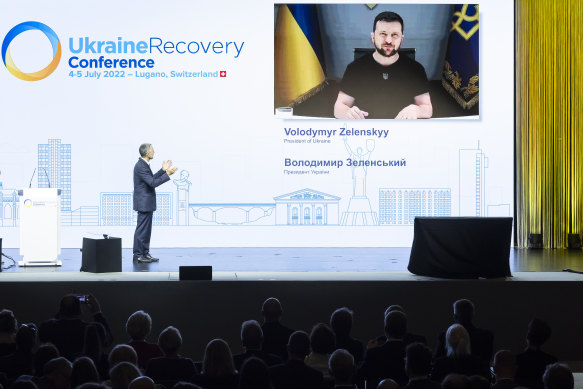 Swiss President Ignazio Cassis, left, introduces Ukrainian President Volodymyr Zelensky, delivering a speech by video, at the Ukraine Recovery Conference, in Lugano on Monday.