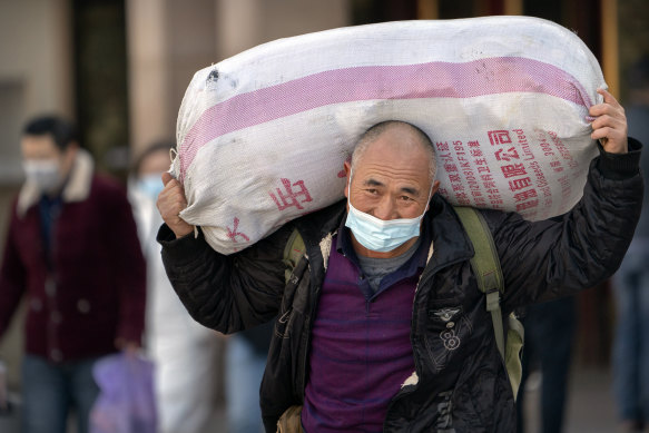 A traveller wearing a face mask to protect against the spread of the coronavirus carries his luggage at the Beijing Railway Station on Thursday.