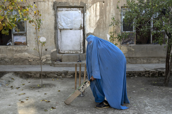 An Afghan woman poses for a photo with her cricket bat in Kabul in 2022.