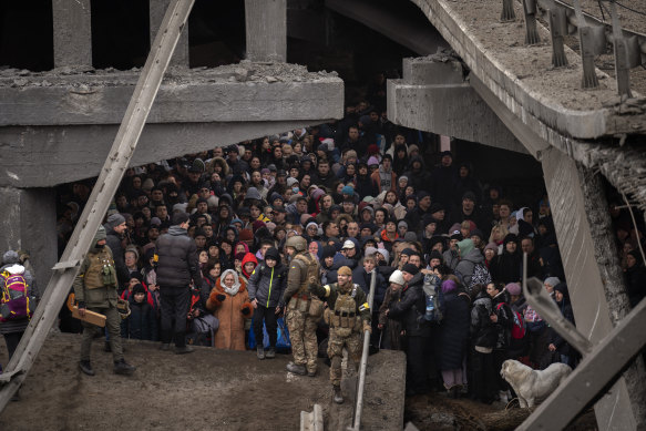Ukrainians crowd under a destroyed bridge as they try to flee crossing the Irpin river in the outskirts of Kyiv, Ukraine.