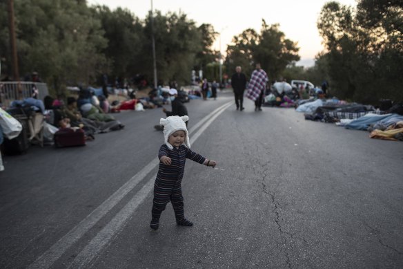A boy tries to stand as migrants sleep on the road near the Moria refugee camp on the island of Lesbos, Greece, on Thursday.