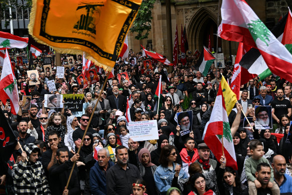 Demonstrators hold Hezbollah flags and pictures of the late Hassan Nasrallah at the rally in Sydney last Sunday. 