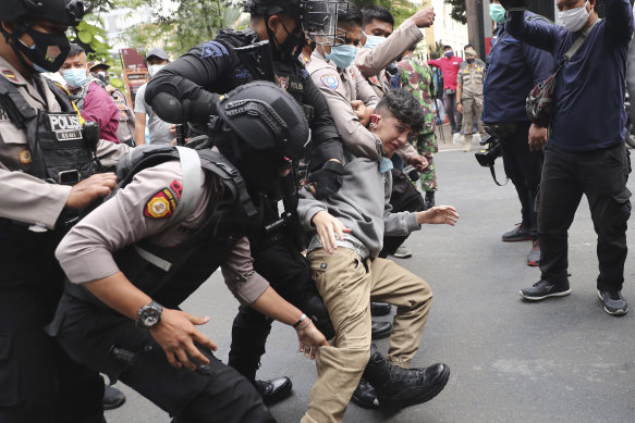 Police officers scuffle with an Afghan refugee during a rally outside the building that houses the UNHCR representative office in Jakarta, Indonesia, on Tuesday, August 24, 2021. 