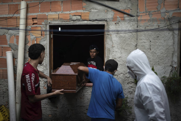 Relatives help a funeral worker, wearing protective gear, remove a body from a home in Manaus, Brazil, last year.