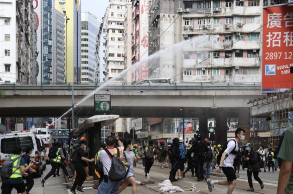 A police water cannon sprays water as journalists and demonstrators run during a protest against a planned national security law in Hong Kong, China, on Sunday.