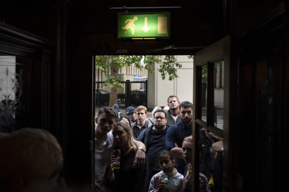 Crowds gather outside a London pub to watch the King’s first speech.