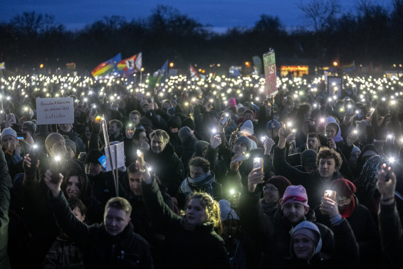People raise their mobile phones as they protest against the AfD and right-wing extremism in front of the Reichstag building in Berlin, Germany.