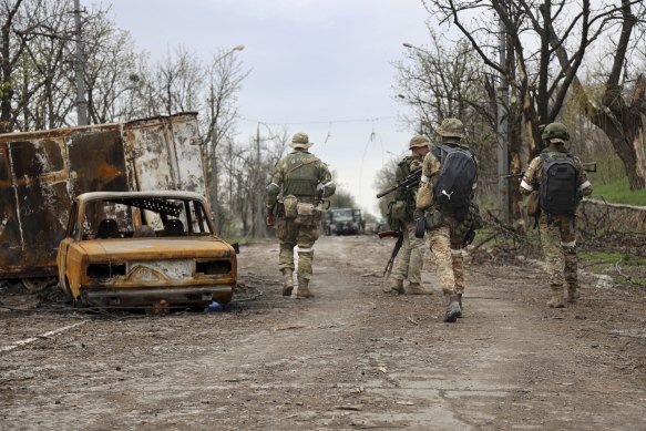 Republic militia walk past damaged vehicles during a heavy fighting in an area controlled by Russian-backed separatist forces in Mariupol.