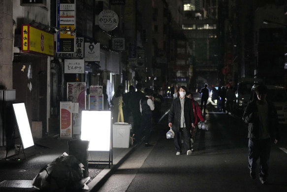 People walk on a street during a black-out in Tokyo on Thursday.