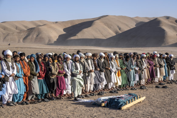 Afghans pray for relatives killed in an earthquake to a burial site after an earthquake in Zenda Jan.