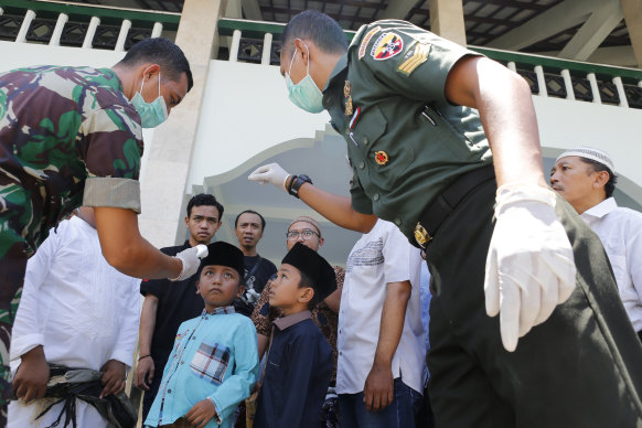 Military officials check the body temperature of a boy before prayers at a mosque in Bali, Indonesia last Friday.
