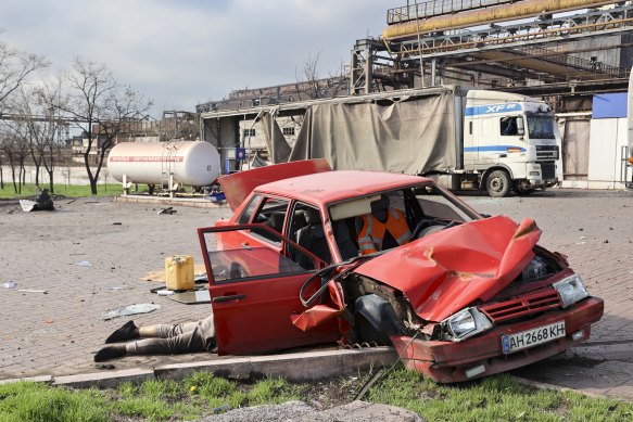 A body of a civilian lies next to a damaged car in an area controlled by Russian-backed separatist forces in Mariupol.