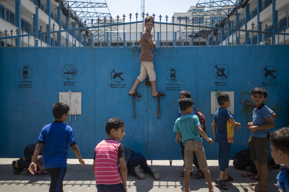 Palestinian schoolboys try to look from the door of a United Nations-run primary school at damage caused by an explosion in Gaza City.