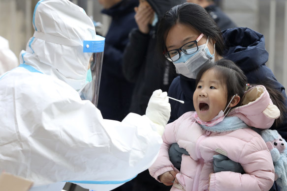 A worker in a protective suit takes a swab from a child for a coronavirus test in Shijiazhuang in China’s Hebei Province last year. 