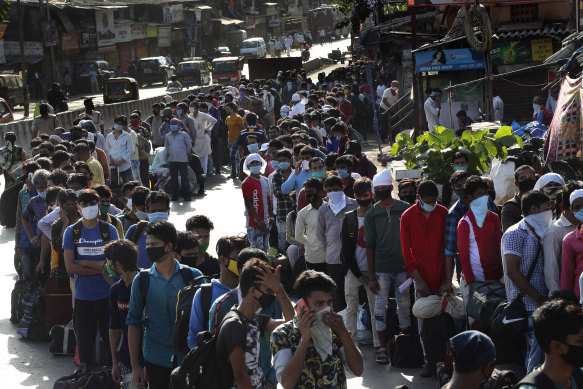 Migrant workers line up to board buses in India after restrictions were eased in May last year, allowing them to return to their home states. 