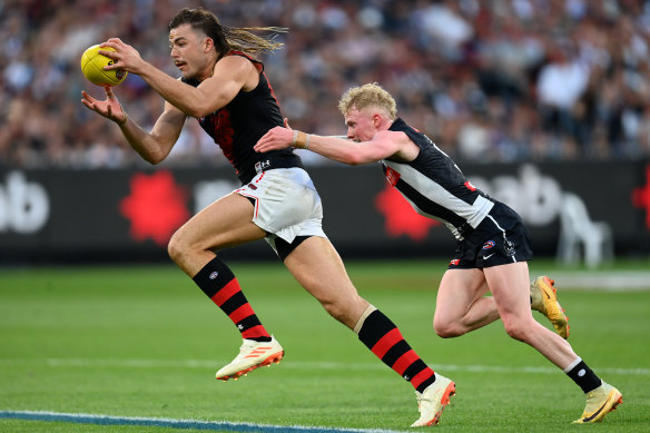 Essendon’s Sam Draper is tackled by Collingwood’s John Noble. 