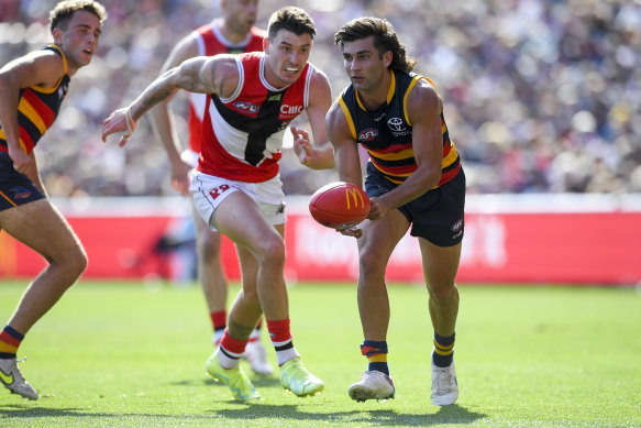 Josh Rachele of the Crows handballs in front of Josh Battle.