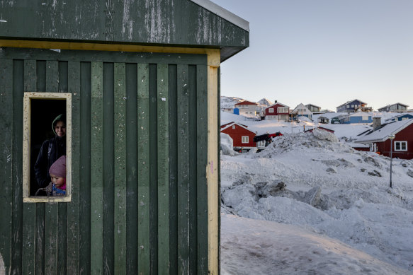 A young Inuit girl and her mother wait inside a bus shelter in Nuuk, Greenland.