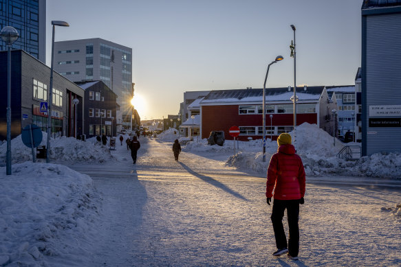 People walk through the center of Nuuk, Greenland, during the short daylight hours that the town gets at this time of year, 