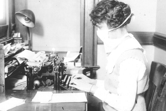 A typist wears a mask while working at her desk during the Spanish flu epidemic in 1918. 