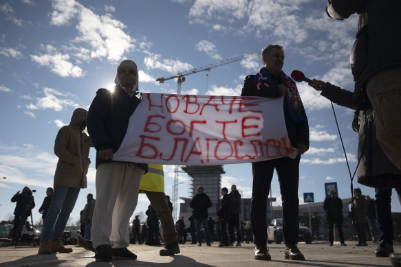 People hold a banner reading “Novak, God bless you” as they wait outside the VIP exit of Belgrade’s international airport.