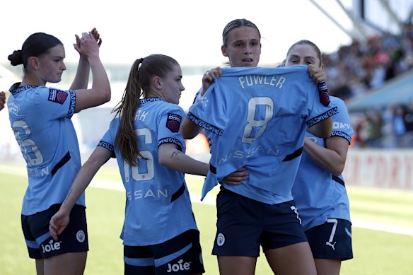 Teammates hold up Mary Fowler’s jersey in tribute to her shortly after her injury.