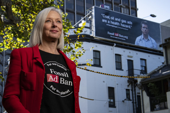 Comms Declare CEO Belinda Noble with a billboard in Sydney promoting the organisation’s “Fossil Fuel Ad Ban” campaign.