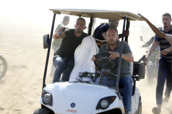 A captured Israeli civilian from Kibbutz Kfar Azza, wrapped in white, being taken into the Gaza Strip.