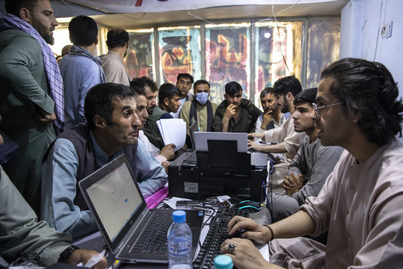 Afghans crowd into the Herat Kabul internet cafe to apply for visas. 