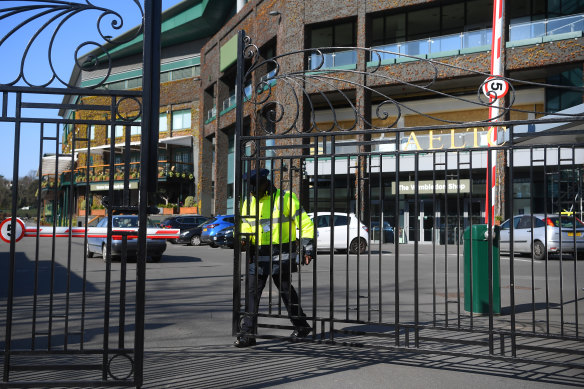 A security guard shuts the gates of The All England Tennis and Croquet Club on Wednesday.